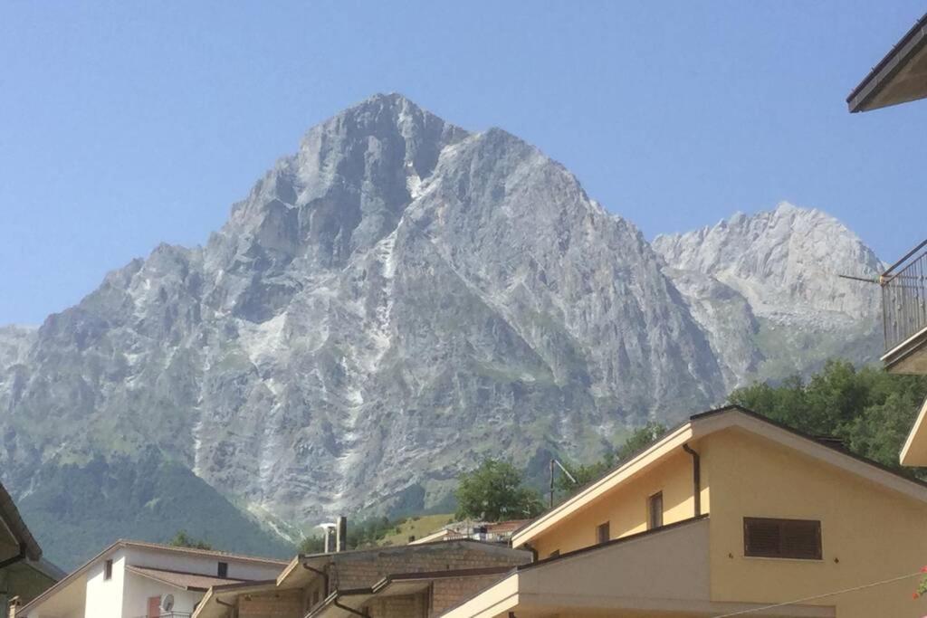 Une montagne au loin avec des maisons devant elle dans l'établissement La montagna incantata, à Isola del Gran Sasso dʼItalia