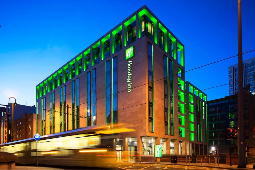 un edificio con luces verdes en el lateral. en Holiday Inn Manchester - City Centre, an IHG Hotel, en Mánchester