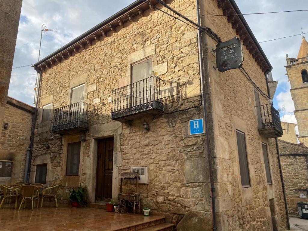 a stone building with two balconies and a table at Hotel rural Rinconada de las Arribes in Aldeadávila de la Ribera