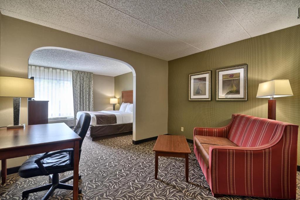 a hotel room with a bed and a desk and a chair at Clarion Inn & Suites - University Area in Cortland