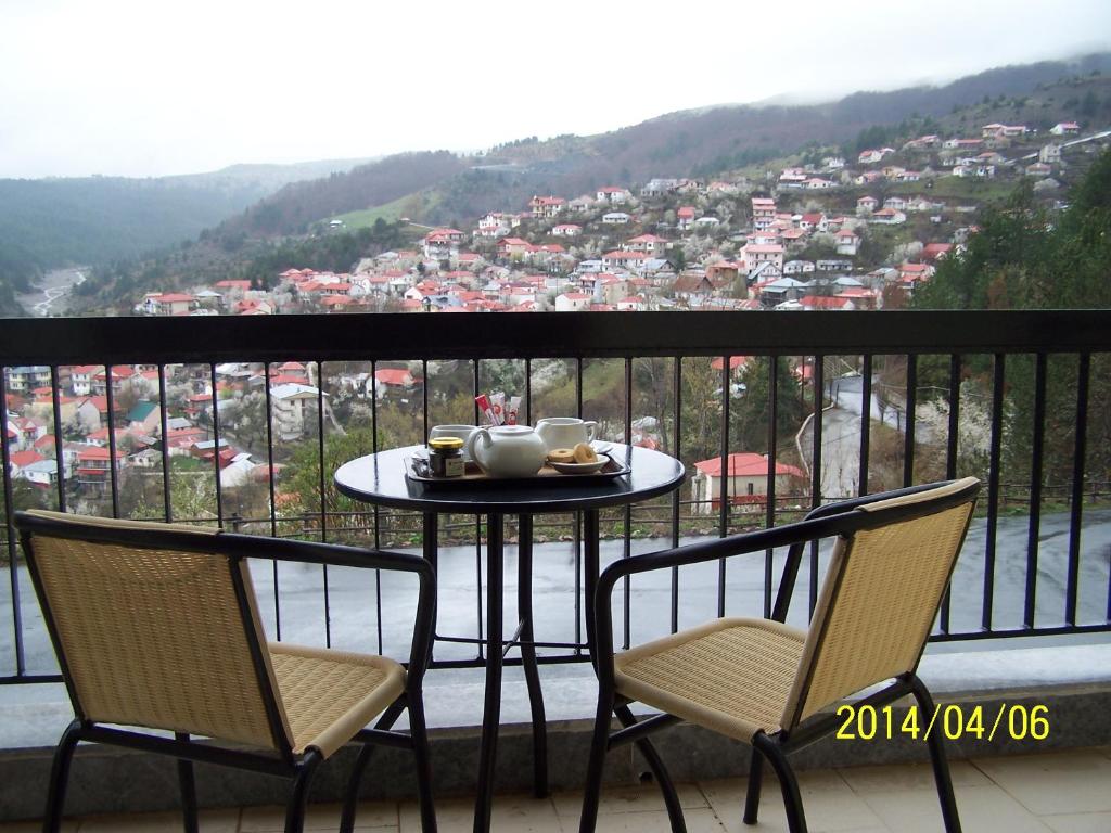 einen Tisch und Stühle auf einem Balkon mit Aussicht in der Unterkunft Valia Calda Hotel in Perivoli