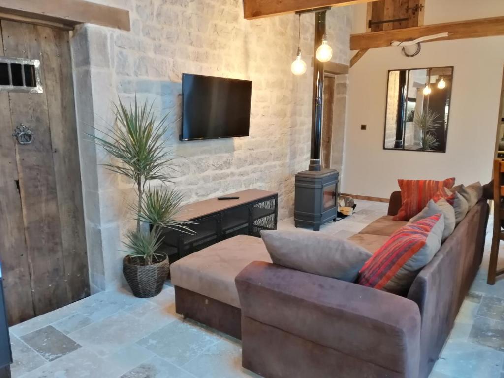 sala de estar con sofá y TV en Gîte Les Hauts de Morey - Aux Bonnes-Mares, en Morey-Saint-Denis