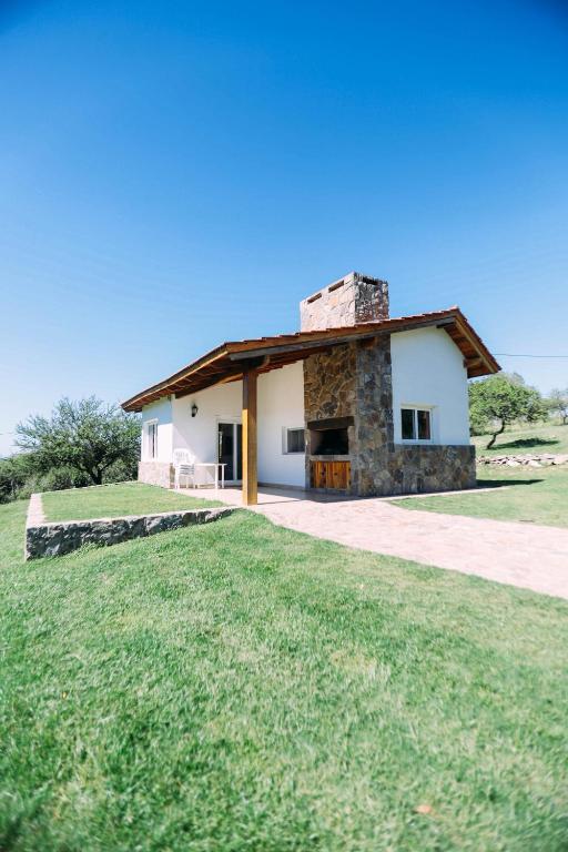 a house with a stone building in a field at Cabaña Sol - FINCA PUDUAM in Villa General Belgrano