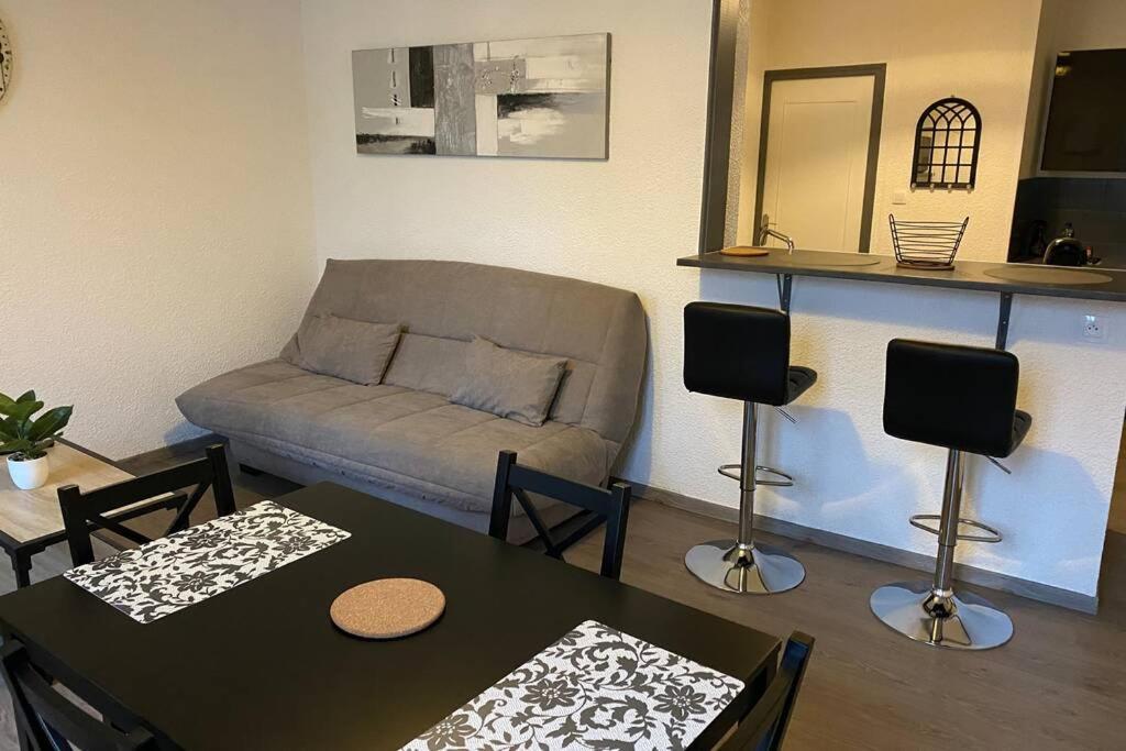 een woonkamer met een bank en een tafel en stoelen bij La bâtisse de Chabot N°5 ( 4 couchages) in Montluçon