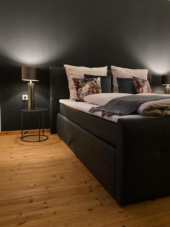 a bed in a bedroom with a black wall at Ferienhaus AusZeit in Bad Bertrich