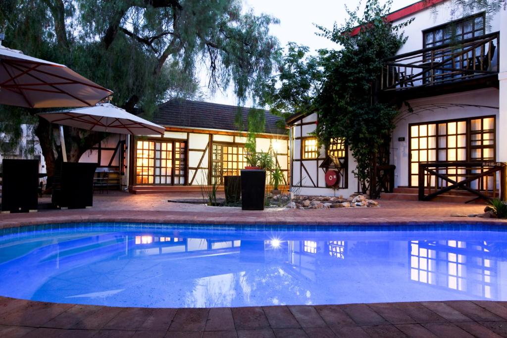 a swimming pool in front of a house at Roof of Africa Hotel in Windhoek