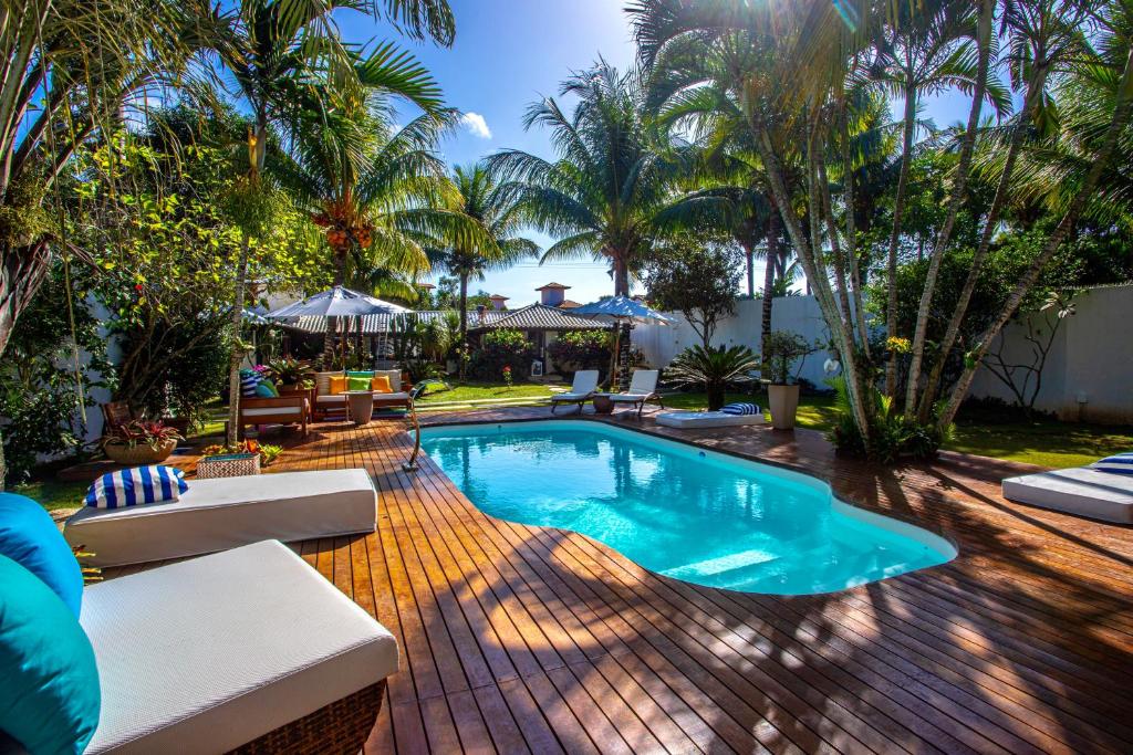 una piscina en un patio trasero con palmeras en Búzios House, en Búzios