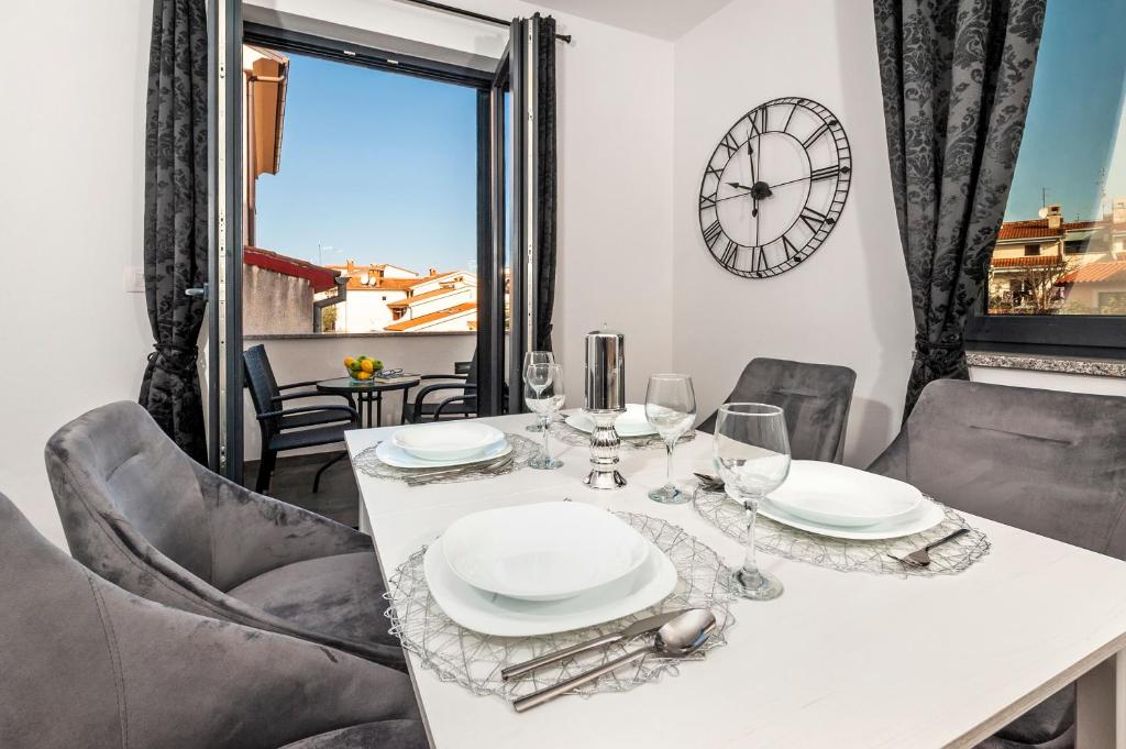 a dining room with a table and chairs and a clock at Deluxe Apartments A&A in Rovinj