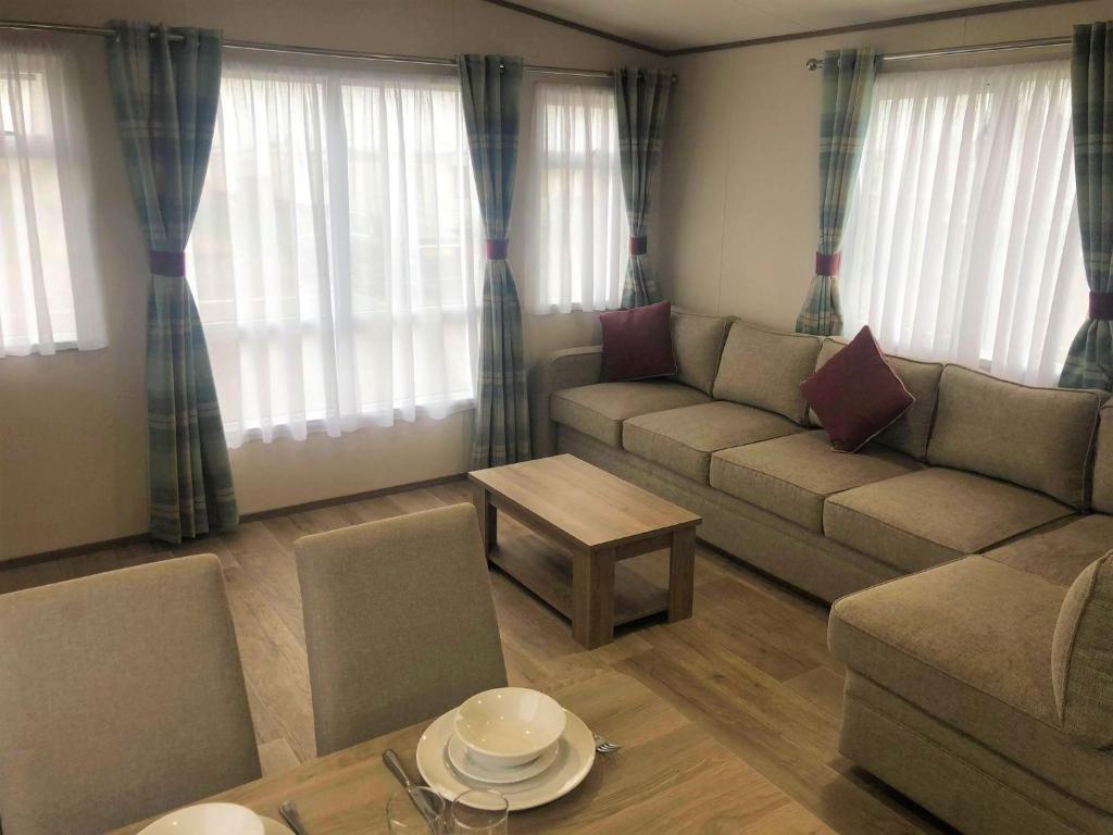 a living room with a couch and a table at Oak Prestige Holiday Home in Chapel Saint Leonards