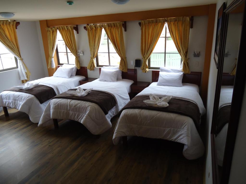 Hotel KUTTY WASI VALLE SAGRADO في أوروبامبا: ثلاثة أسرة في غرفة بها ثلاثة نوافذ