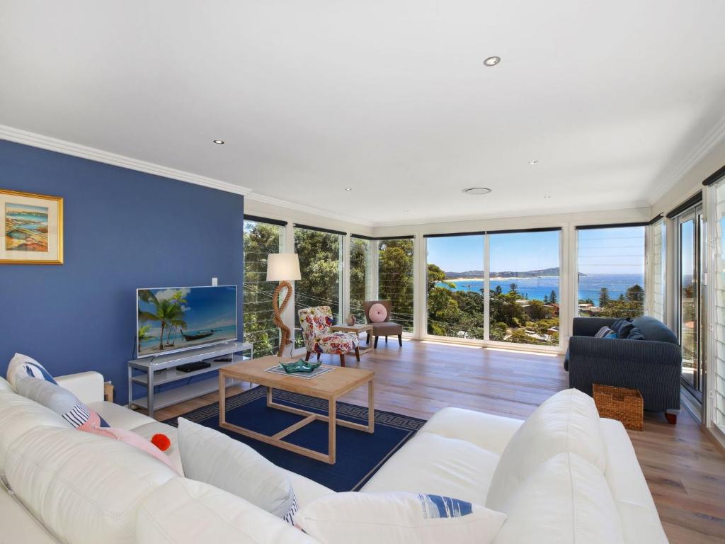 a living room with a white couch and a blue wall at Enjoy Spectacular Oceanviews with BBQ & Airy Space in Terrigal
