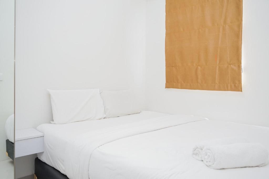 a bedroom with a white bed and a mirror at Comfy 2BR Apartment at Parkland Avenue By Travelio in Babakan