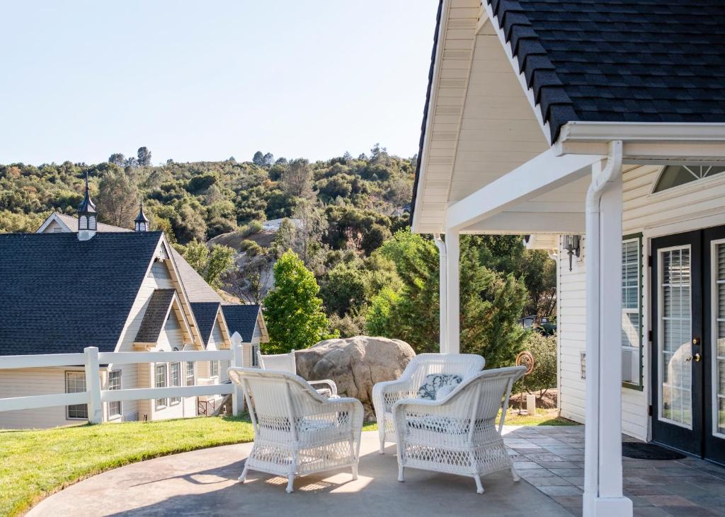 a porch with white chairs and a white fence at Hounds Tooth Inn in Oakhurst