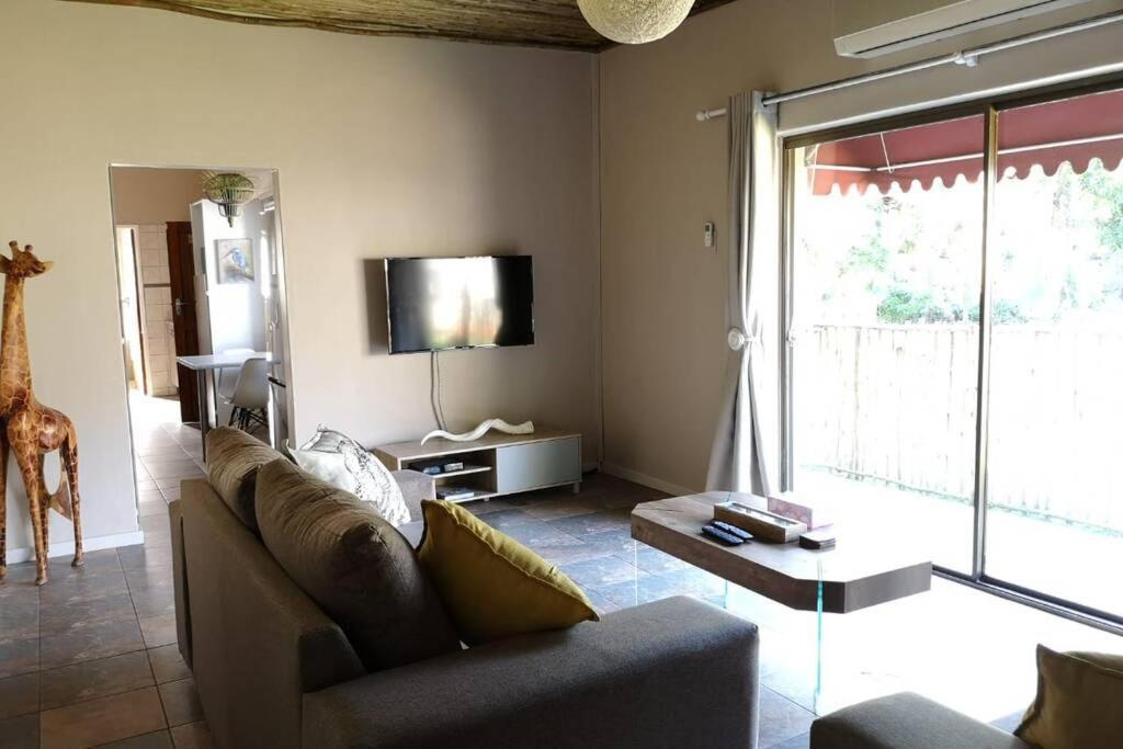 ein Wohnzimmer mit einem Sofa und einem TV in der Unterkunft Ducks Nest in Malelane