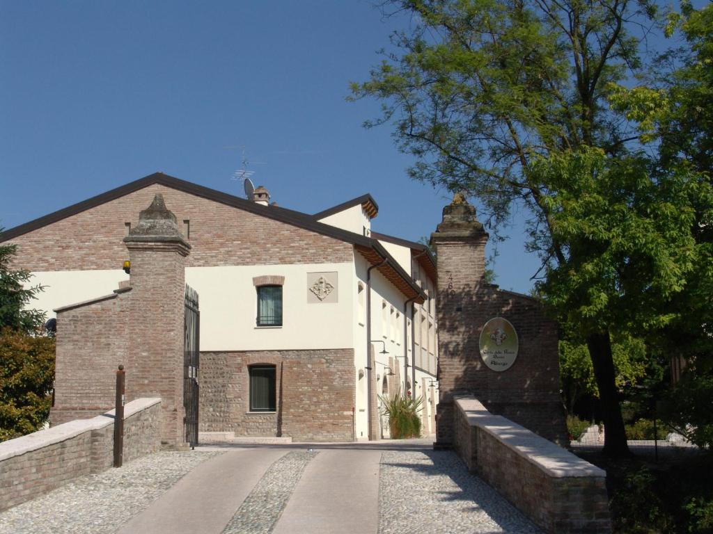 un vieux bâtiment en briques avec un arbre devant lui dans l'établissement Corte Della Rocca Bassa, à Nogarole Rocca