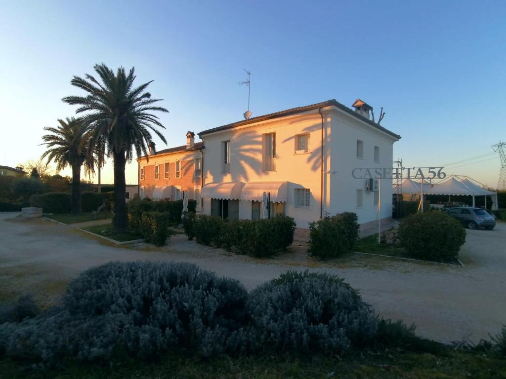 un edificio blanco con una palmera delante en Relais Casetta 56 en Lugo