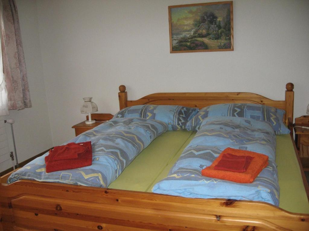 a wooden bed with two red pillows on it at Chalet uf em Stutz 1 in Grindelwald