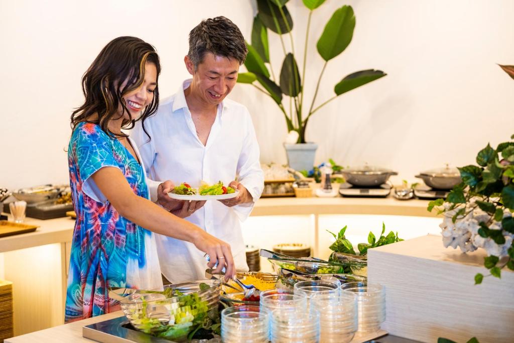 a man and woman standing in a kitchen preparing food at Hotel Torifito Miyakojima Resort in Miyako-jima