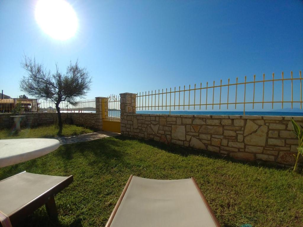 una valla de piedra y una mesa y un banco en un patio en Nikotsaras beach house since 1930 en Acharavi