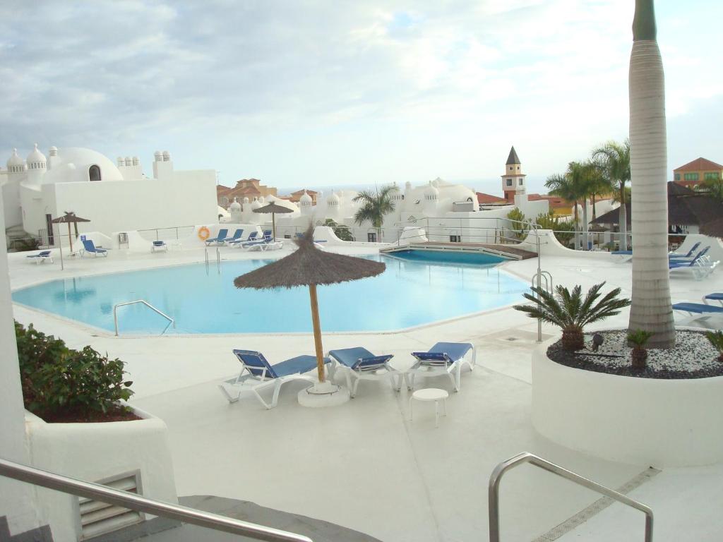 a view of a swimming pool with chairs and an umbrella at Adeje Paradise en Playa Paraiso in Adeje