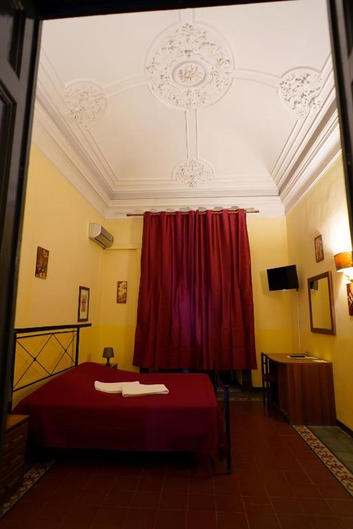a bedroom with a red bed and a red curtain at Hotel Etnea in Catania