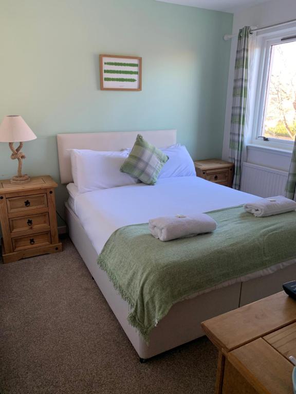 Un dormitorio con una gran cama blanca y una ventana en The Ship Inn, en Invergordon