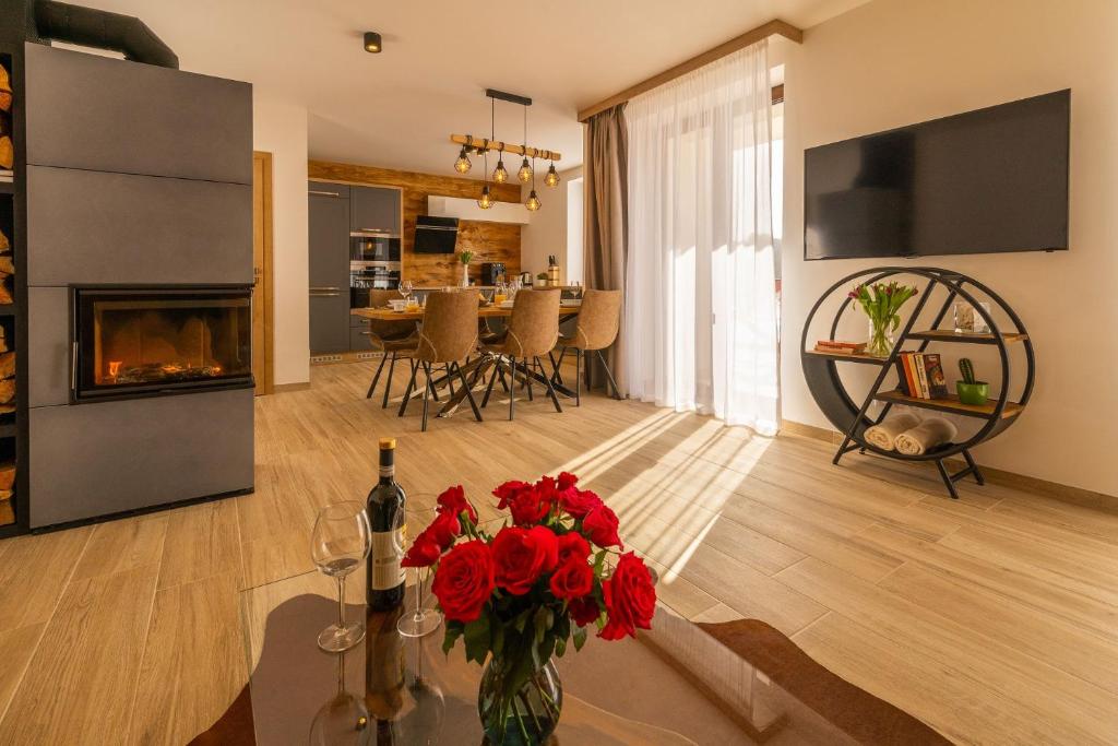 a living room with a fireplace and a table with red flowers at Chalets Gardenia in Donovaly