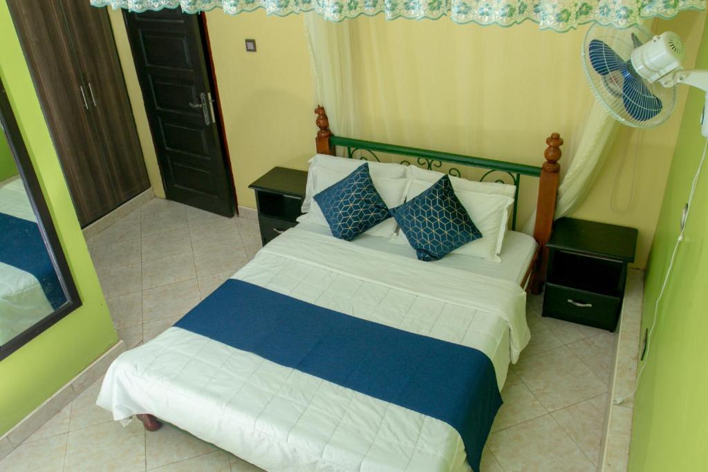 1 dormitorio con 1 cama con almohadas azules y blancas en Seguku Katale Apartment 2, en Kampala