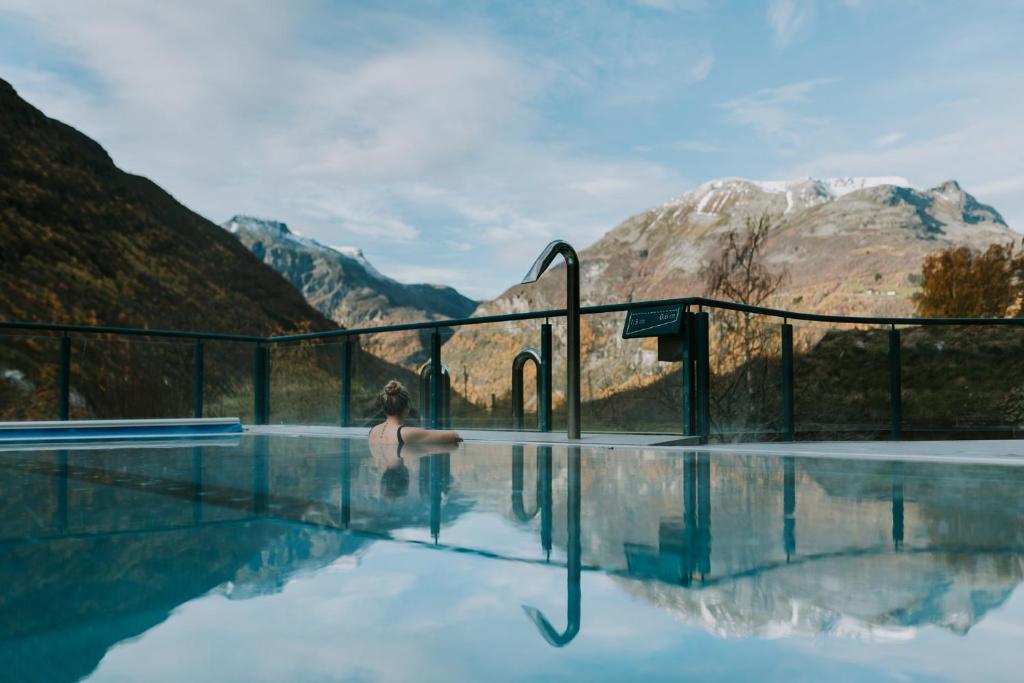 Eine Frau, die in einem Pool aus Wasser in den Bergen steht. in der Unterkunft Hotel Union Geiranger Bad & Spa in Geiranger