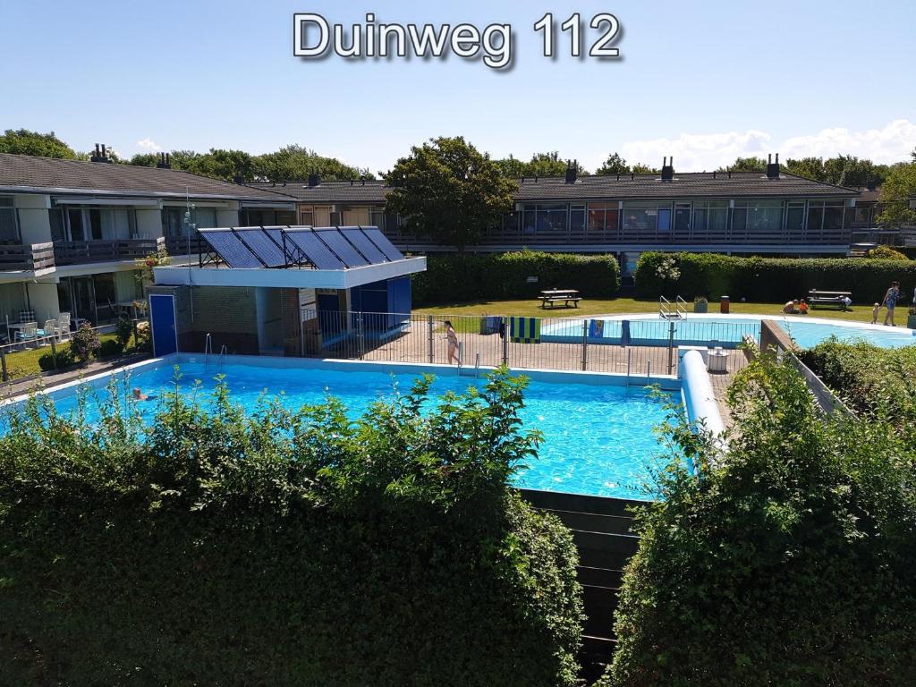a large blue swimming pool in a yard at Appartementen Zuiderstrand in Westkapelle
