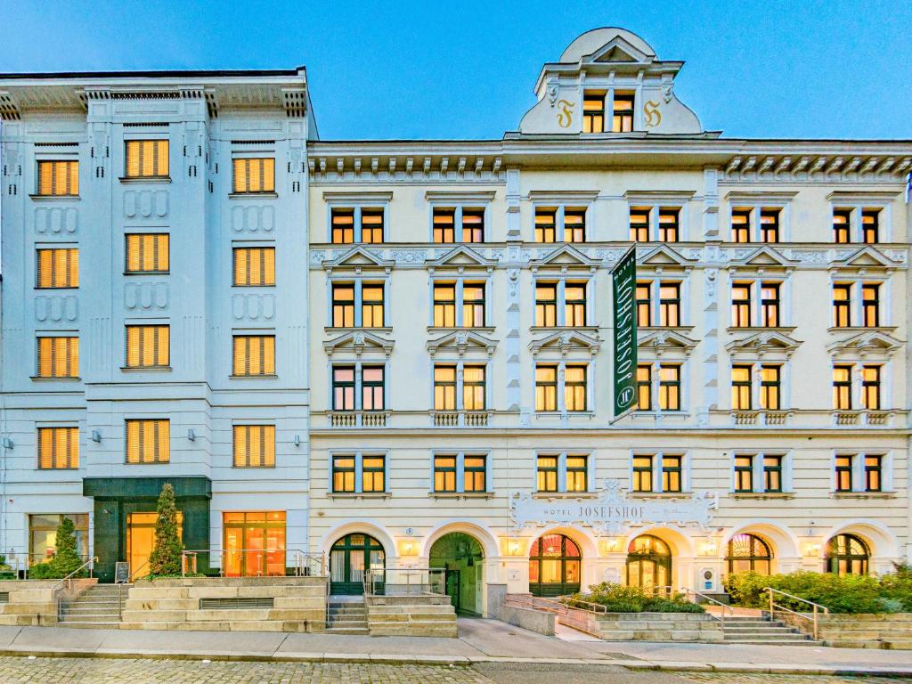 un grande edificio bianco con una torre dell'orologio in cima di Hotel Josefshof am Rathaus a Vienna