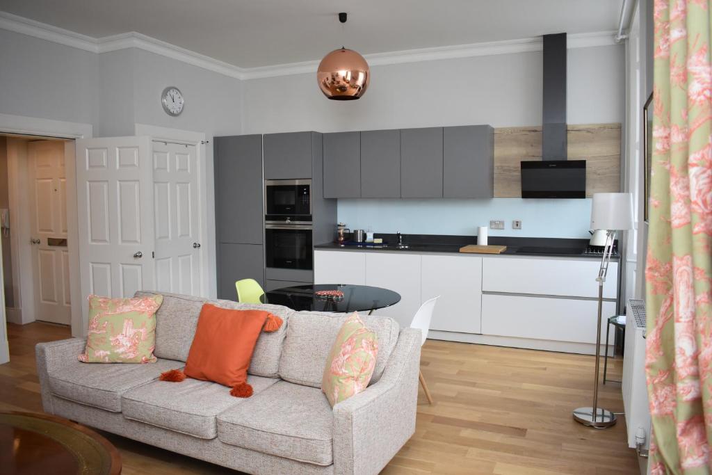 a living room with a couch and a kitchen at Bernard St - Bright and spacious 1 bed apartment at the Shore! in Edinburgh