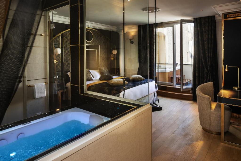 a hotel room with a tub and a bedroom at Paris j'Adore Hotel & Spa in Paris