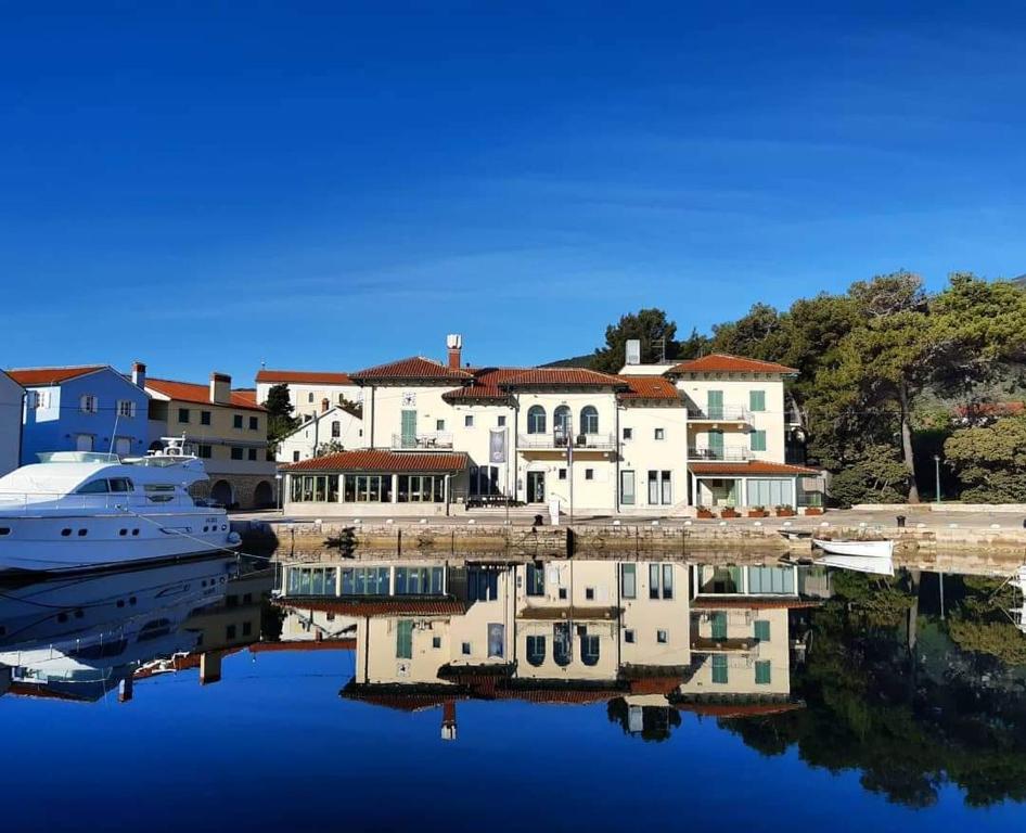a yacht is docked in a harbor with houses at Hotel Televrin in Nerezine
