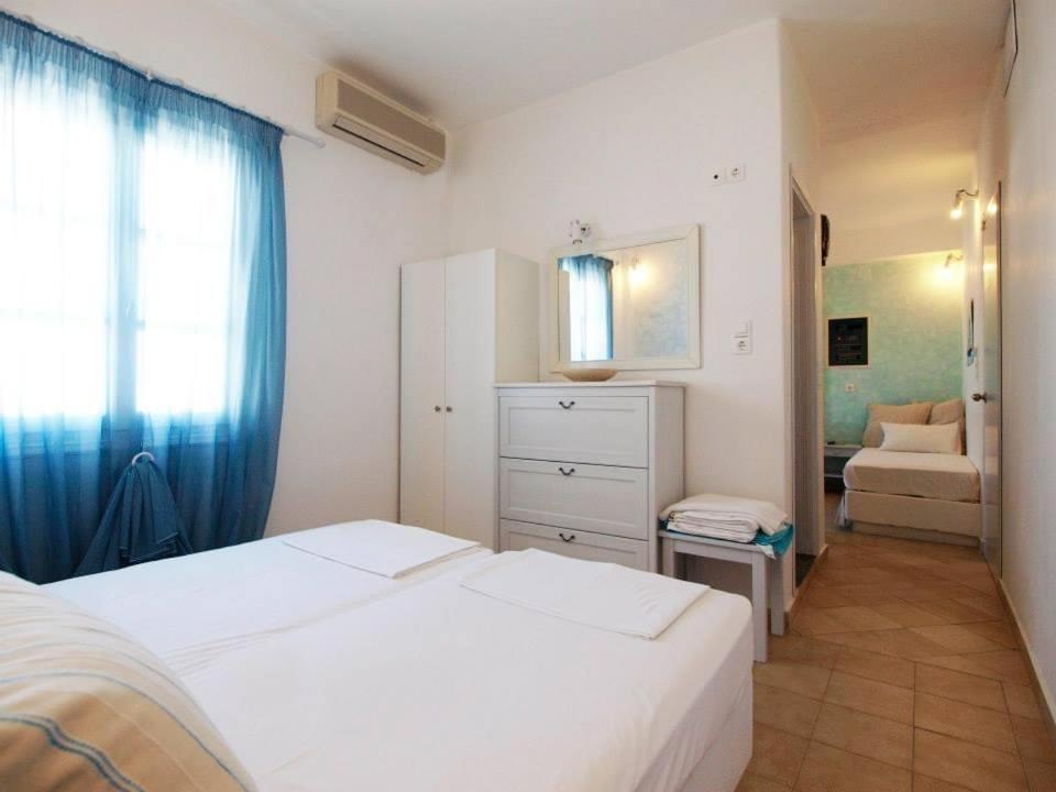 a bedroom with two white beds and a room with a couch at Studio Filareti in Ios Chora