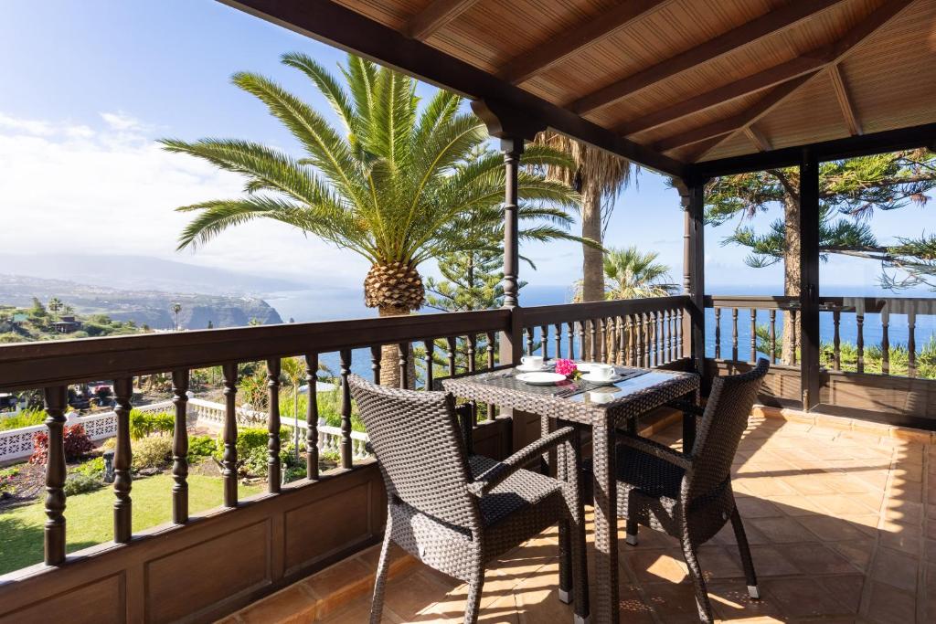 een tafel en stoelen op een balkon met uitzicht op de oceaan bij El Refugio Apartments & Villa in La Matanza de Acentejo