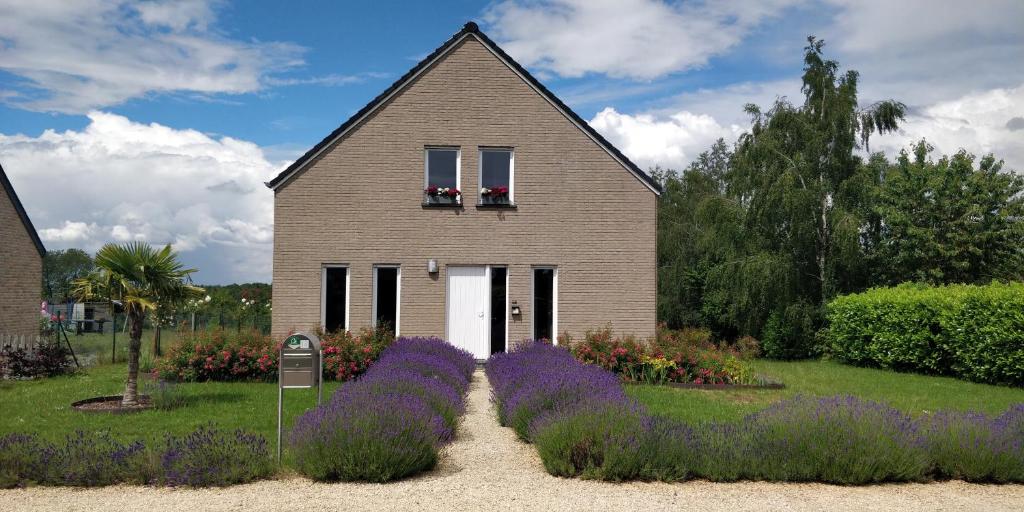 una casa con flores púrpuras delante de ella en Le bordon en Durnal