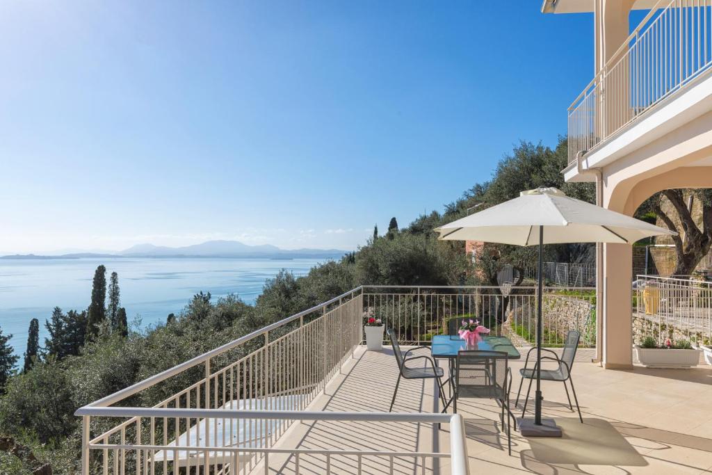 a balcony with a table and chairs and an umbrella at Luna Apartments Corfu in Nisaki