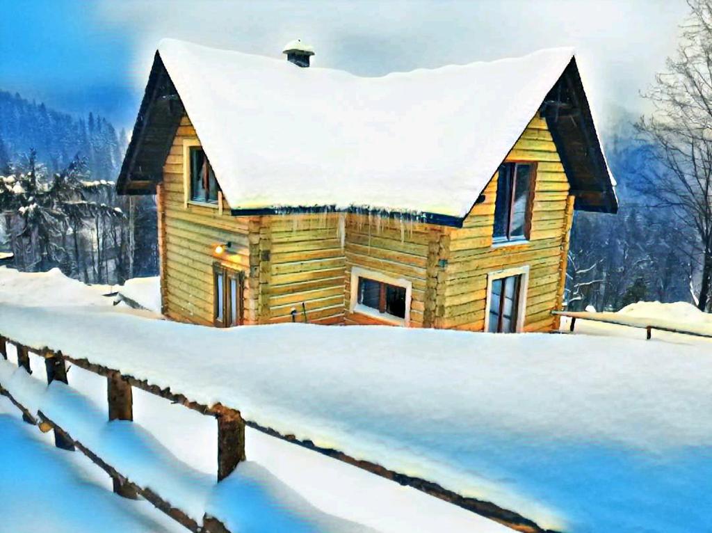 uma casa de madeira coberta de neve com uma cerca em Chata u Pietrka em Szczyrk