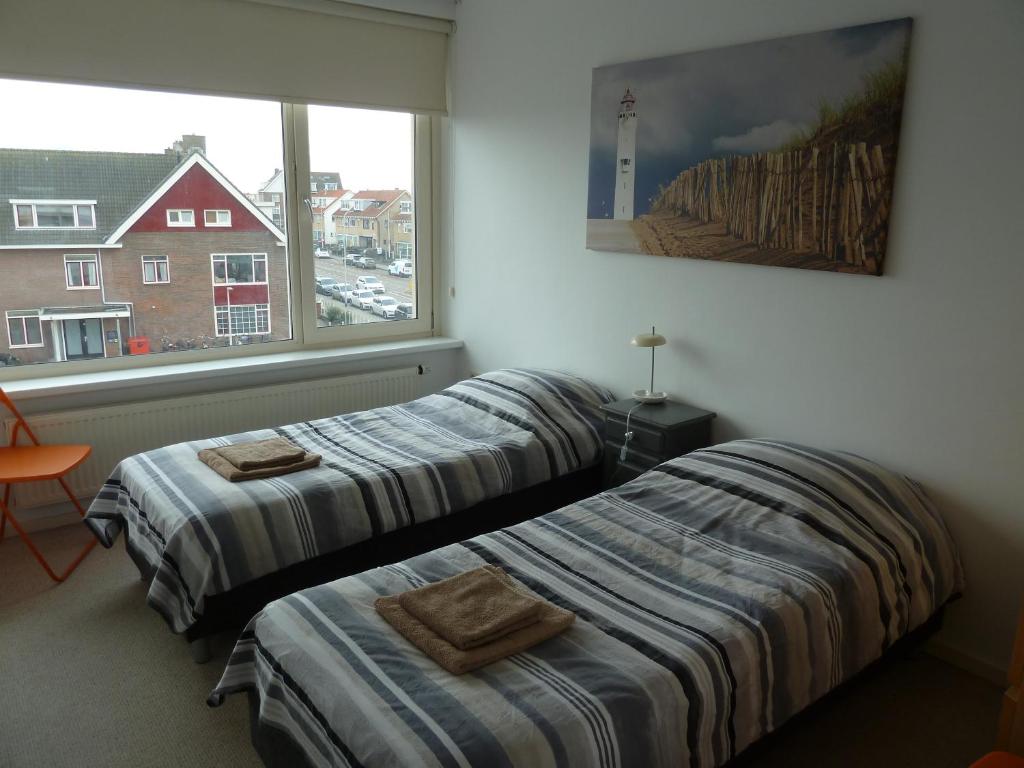 zwei Betten in einem Zimmer mit Fenster in der Unterkunft Appartement "Zicht op de Vuurtoren" in Noordwijk aan Zee