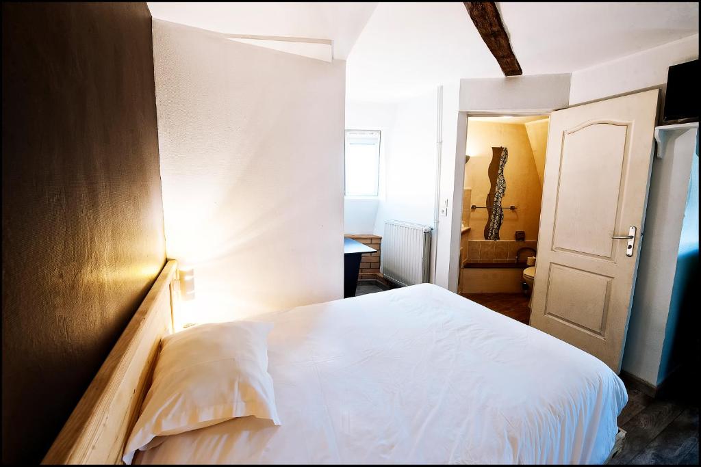 Un dormitorio con una cama blanca con luz. en Hôtel du Nord, en Sainte-Geneviève
