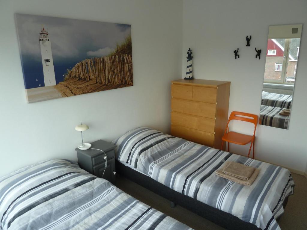2 Betten in einem Schlafzimmer mit einem Bild eines Leuchtturms in der Unterkunft Appartement "Zicht op de Vuurtoren" in Noordwijk aan Zee