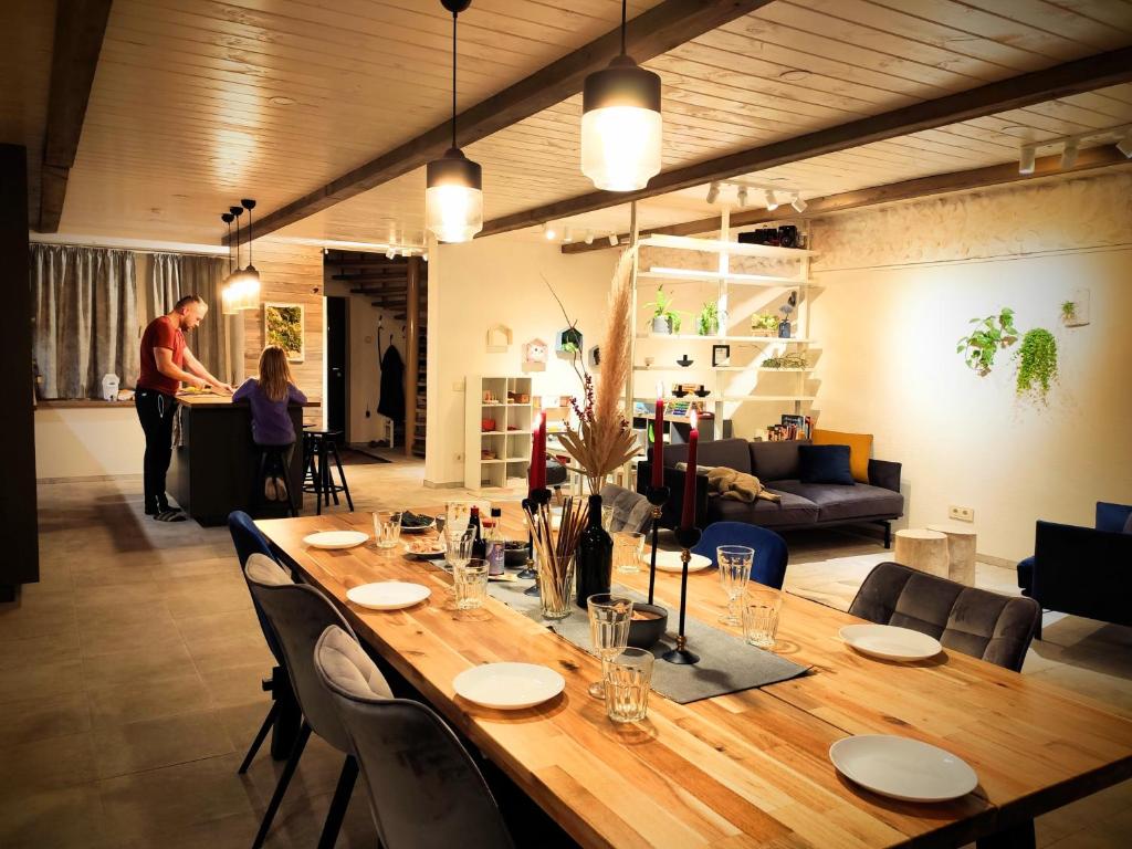 a large wooden table with chairs and a man in a living room at Family house in Druskininkai