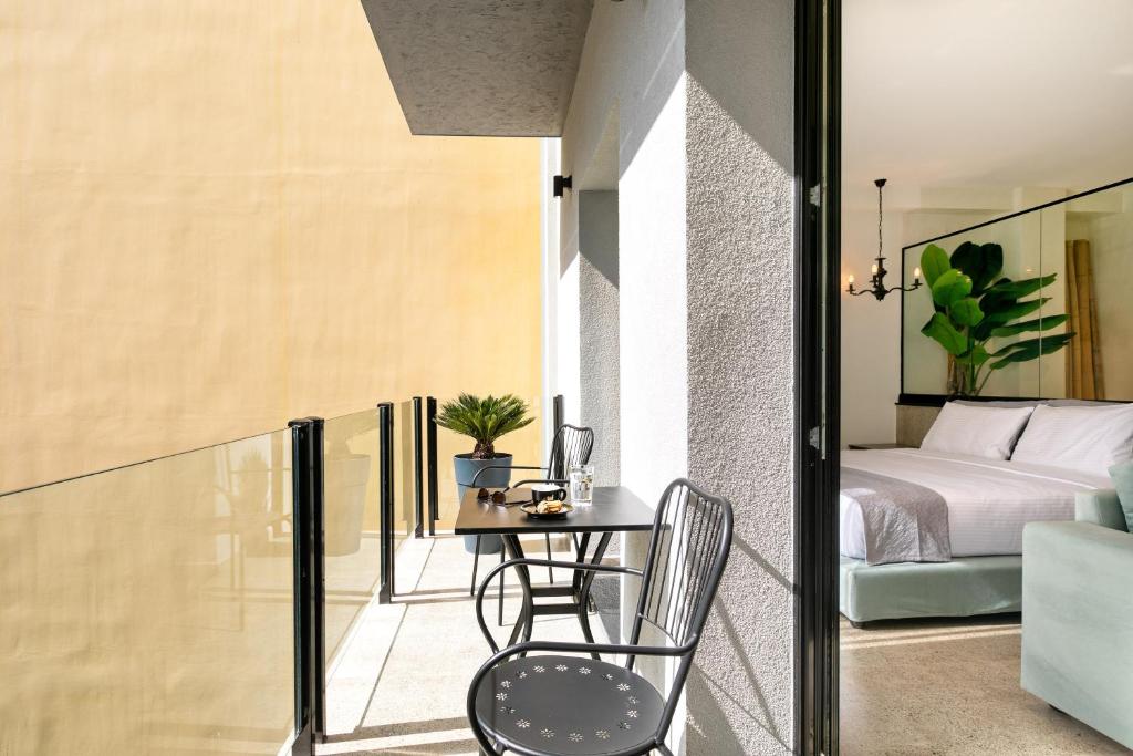 Zimmer mit einem Balkon mit einem Tisch und einem Bett in der Unterkunft Athens Ivy Suites in Athen