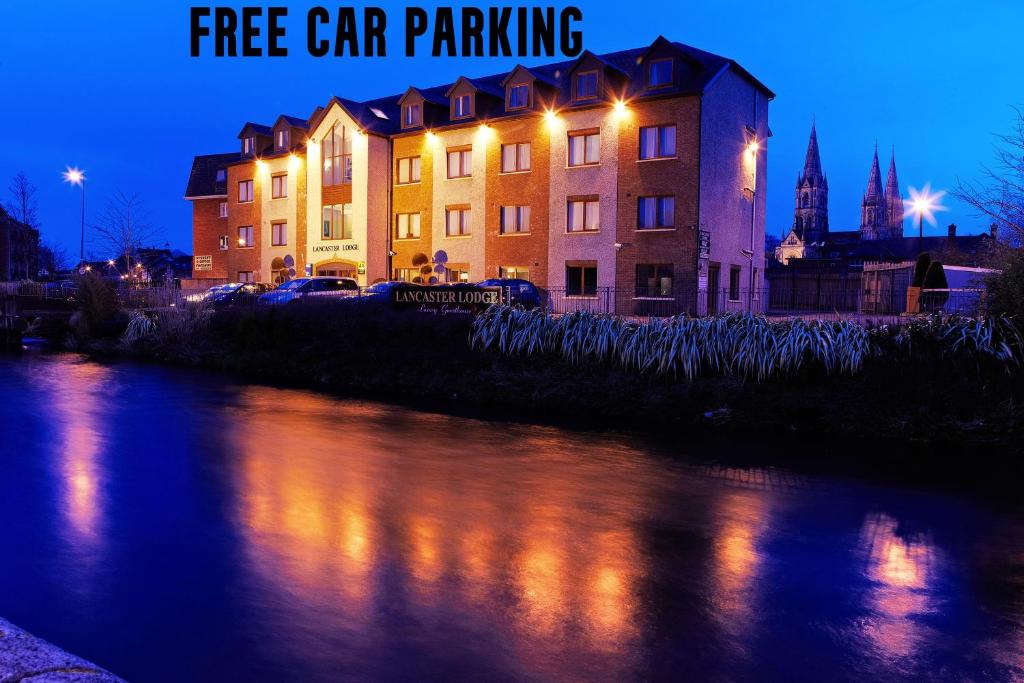 a building next to a river at night with the words free car parking at Lancaster Lodge in Cork