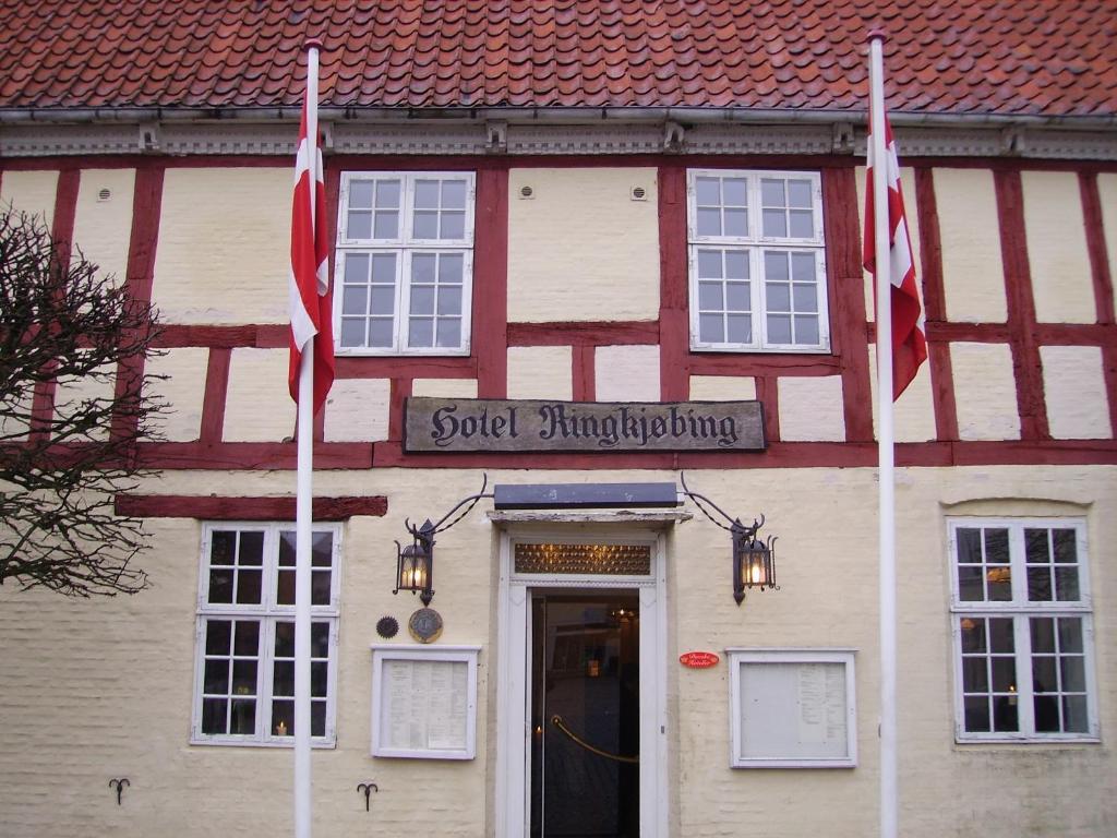 
a red brick building with a flag on the front of it at Hotel Ringkøbing in Ringkøbing
