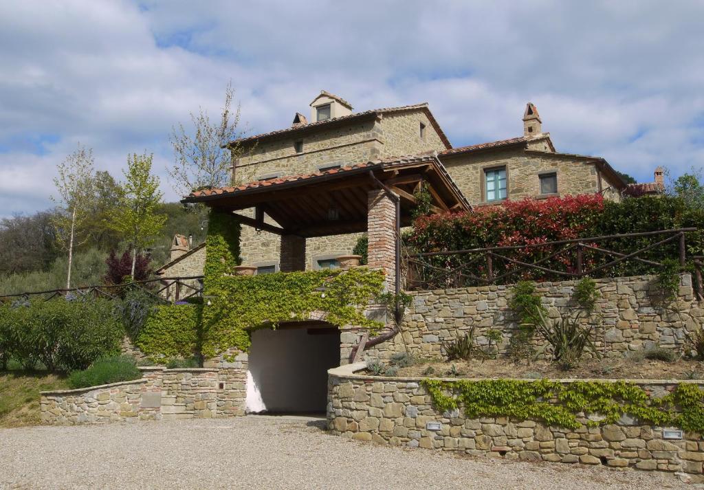 a house with a gate in a stone wall at Villa La Pergola in Cortona