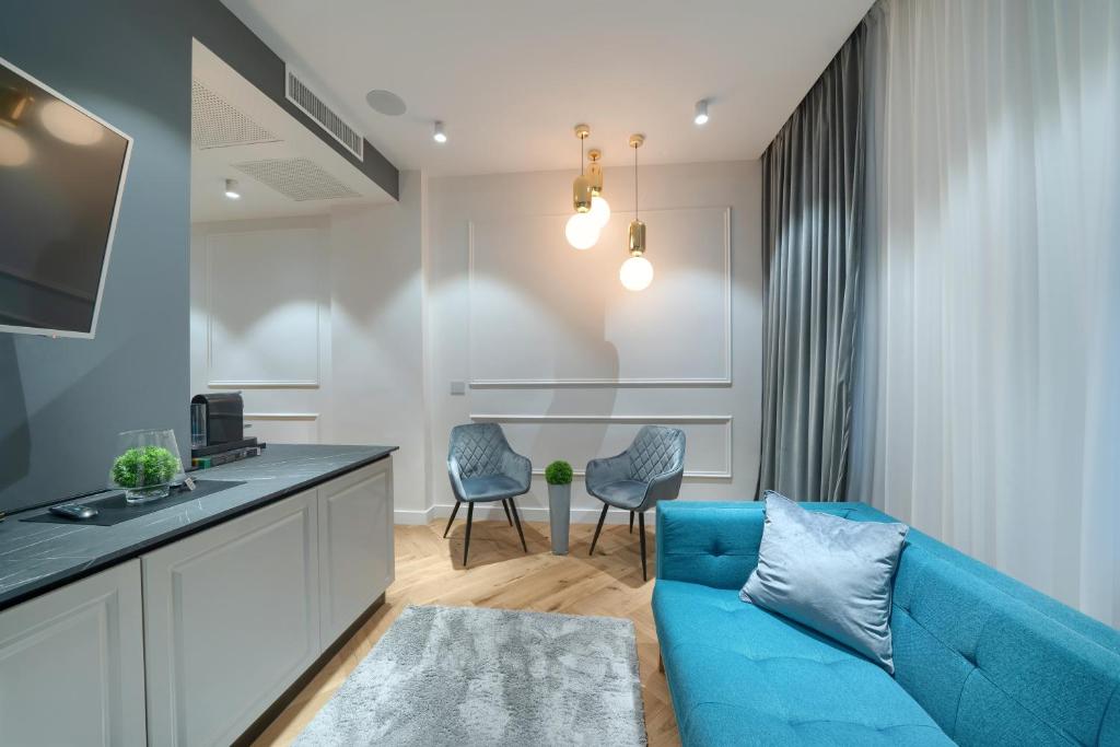 a living room with a blue couch and a kitchen at Elysium Residence in Timişoara