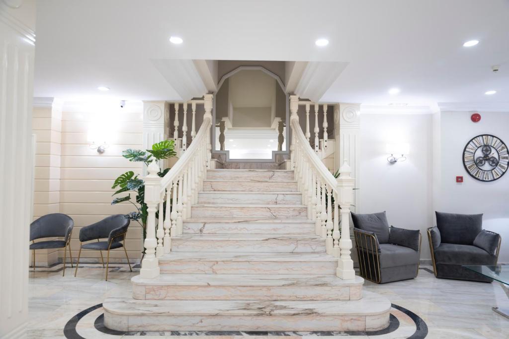 eine Treppe in einer Lobby mit Stühlen und einer Uhr in der Unterkunft Hotel Ramomar in Tomelloso