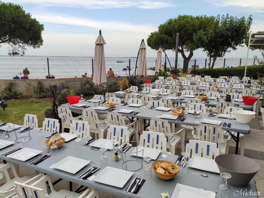 a long table with white chairs and a table with food at Village Club Thalassa in Mèze